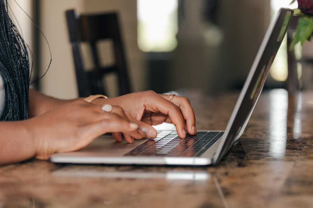 Hands typing on a laptop for a guide to Shopify WebMCP and AI shopping